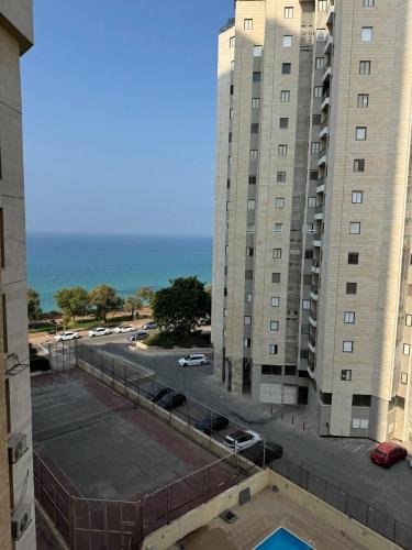 a tennis court in front of a large building at Beach apartment on Nitsa street in Netanya