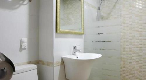 Un baño blanco con lavabo y ducha. en Ewha Hotel, en Jeju