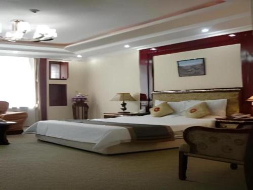 een slaapkamer met een groot bed en een stoel bij Wutaishan Wufeng Hotel in Wutai