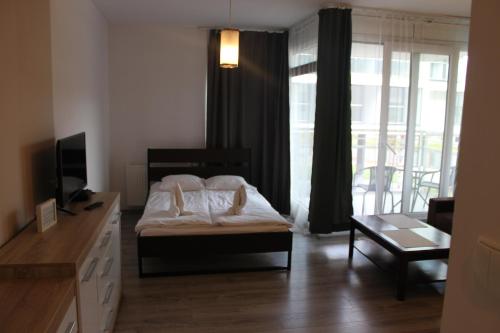 a bedroom with a bed and a desk with a television at Apartament Sadowa in Gdańsk