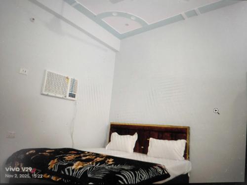 a bedroom with a bed and a white wall at Hotel O Surya Hotel in Kākori