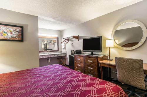 a hotel room with a bed and a desk with a tv at Econo Lodge Tallahassee I-10 near University in Tallahassee