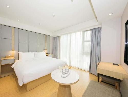 a bedroom with a large white bed and a table at JI Hotel Beijing Changyang Subway Station in Fangshan