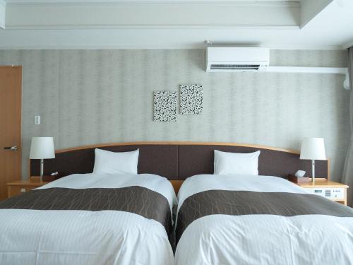 two beds sitting next to each other in a room at GLOBAL RESORT NUKUI in Akiota
