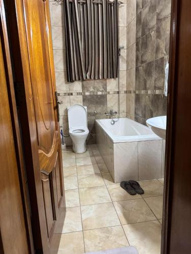 a bathroom with a toilet and a tub and a sink at Dafrican BnB villa in Kigali