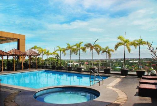 una piscina en un hotel con palmeras en Grand Qin Hotel Syariah, en Martapura