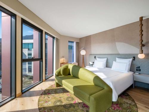 1 dormitorio con 1 cama grande y 1 sofá verde en Swissôtel Tbilisi, en Tiflis