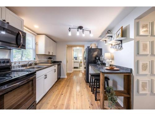a kitchen with white cabinets and a black refrigerator at Downtown Bungalow Less than 1.5 Miles to UGA in Athens