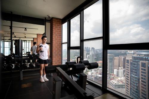 Un hombre de pie en un gimnasio mirando la ciudad. en Ceylonz Leisure Suites KLCC Bukit Bintang, en Kuala Lumpur