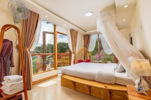 een slaapkamer met een hemelbed en een balkon bij Da Lat Cam Ly Hotel in Ấp Kim Thạch