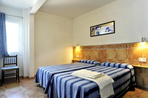 1 dormitorio con 1 cama con manta de rayas azul y blanco en Apartaments El Berganti en Canyelles Petites en Roses