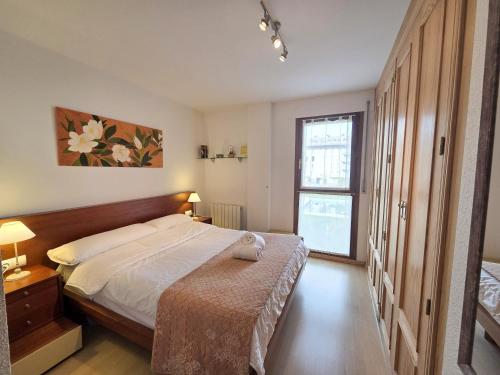 een slaapkamer met een groot bed en een raam bij Apartamentos Pilartxo Jaca 3000 in Jaca