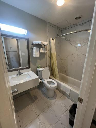 a bathroom with a toilet and a sink and a tub at Cloud 9 Inn - El Ciello Inn in Pico Rivera