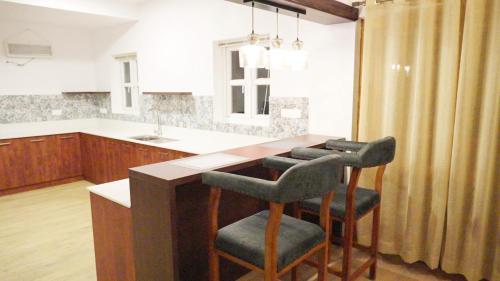 una cocina con una isla con dos taburetes y una barra en 3 Bhk Villa Ooty - Casa de Amor by EBR, en Ooty