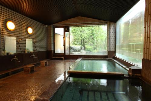 an indoor pool in a bathroom with a large window at Yudanaka Yumoto in Yamanouchi