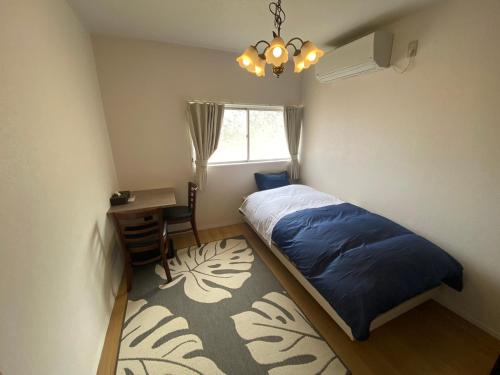 een slaapkamer met een bed, een bureau en een raam bij やどかり852 in Manazuru