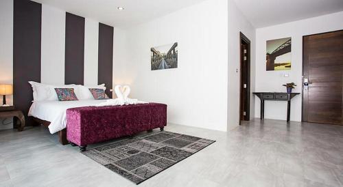 a bedroom with a white bed and a purple ottoman at The Bridge Residence Hotel in Kanchanaburi