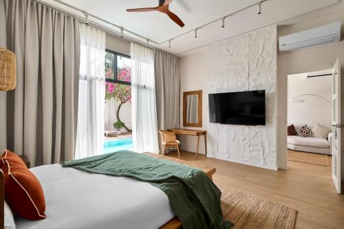 a bedroom with a bed and a tv on a wall at Onyx Villas by TropicLook in Nai Harn Beach