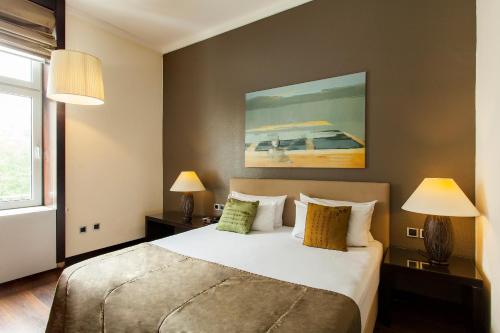 a bedroom with a bed with two lamps and a painting at Quentin Design Hotel Berlin in Berlin