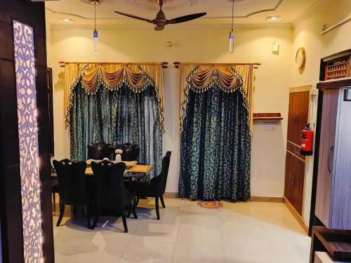 a dining room with a table and chairs and curtains at Urban Retreat in Agra