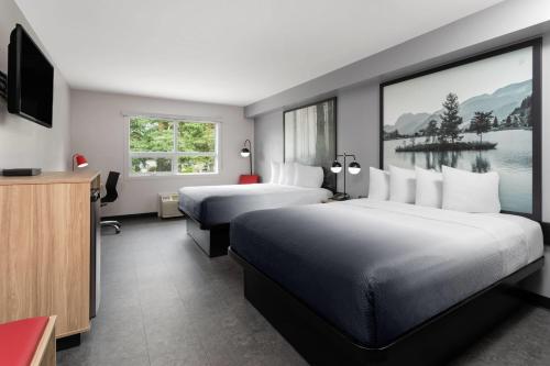 Una habitación de hotel con dos camas y un televisor. en Super 8 by Wyndham Sault Ste Marie On, en Sault Ste. Marie