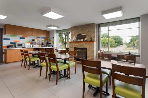 a dining room with tables and chairs and a kitchen at Super 8 by Wyndham Sault Ste Marie On in Sault Ste. Marie