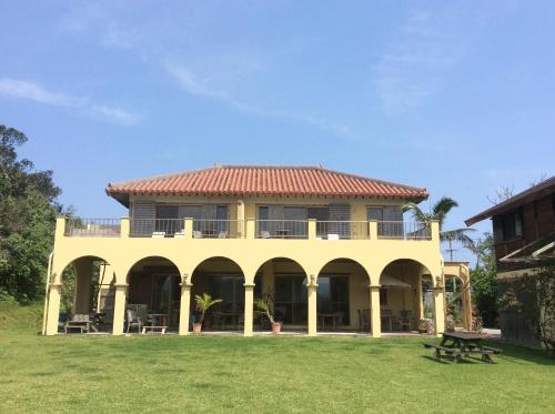 a large yellow house with a red roof at Mayagusuku Resort in Iriomote