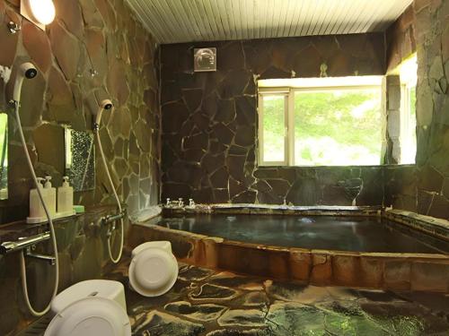 a bathroom with a tub with a toilet and a window at Yumekiko in Nasushiobara