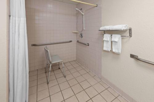 a shower with a chair in a bathroom at Ramada by Wyndham Grayling Hotel & Conference Center in Grayling