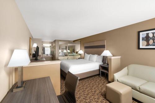 a hotel room with a bed and a couch and a chair at Hawthorn Suites by Wyndham Napa Valley in Napa
