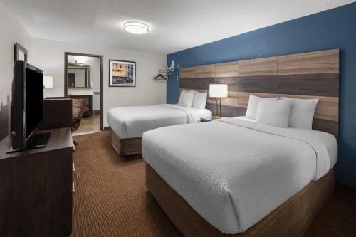 a hotel room with two beds and a flat screen tv at Baymont by Wyndham Downtown Detroit in Detroit