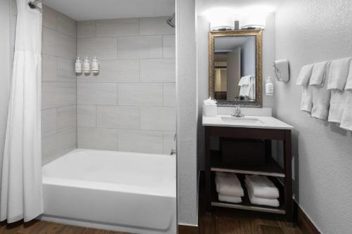 a bathroom with a tub and a sink and a shower at Baymont by Wyndham Downtown Detroit in Detroit