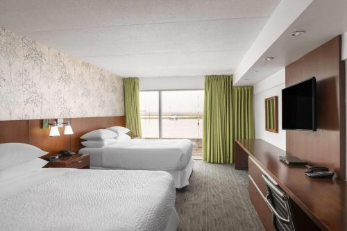 a hotel room with two beds and a flat screen tv at Lakeview Signature, Trademark Collection by Wyndham in Winnipeg