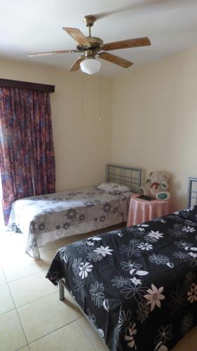 a bedroom with two beds and a ceiling fan at Kalampakas Guesthouse in Larnaka
