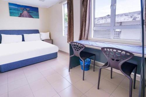 a bedroom with a bed and a desk and a window at Station Hotel Klang in Klang