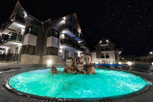 un homme et trois enfants dans une piscine la nuit dans l'établissement Czarny Kamień Resort & SPA, à Szklarska Poręba