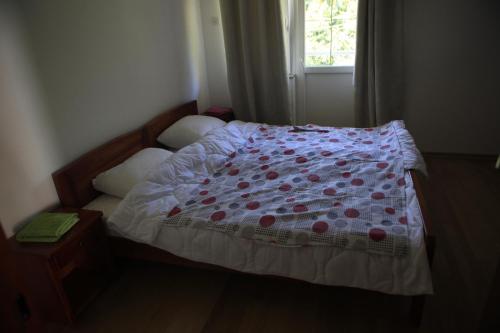 - une chambre avec un lit doté d'une couverture fleurie et d'une fenêtre dans l'établissement Apartment Mitric, à Plužine
