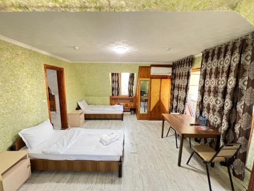 a bedroom with two beds and a desk and a table at The green regency in Toshkent-Passajir Bekati