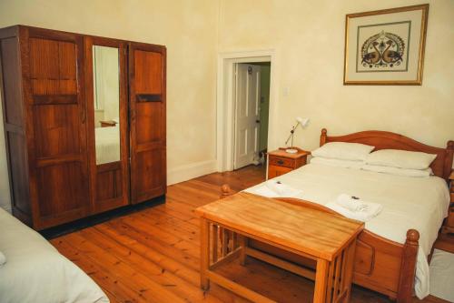 a bedroom with a bed and a table in it at Wilgewandel Holiday Farm & Day Restaurant in Oudtshoorn