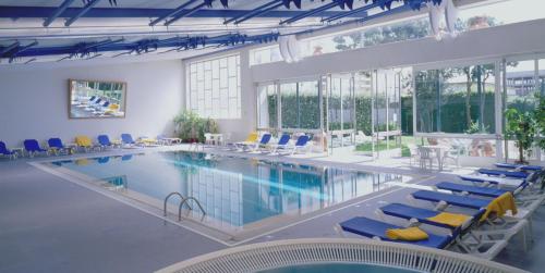 a large swimming pool with blue and yellow chairs at Golden Tulip Porto Gaia in Vila Nova de Gaia