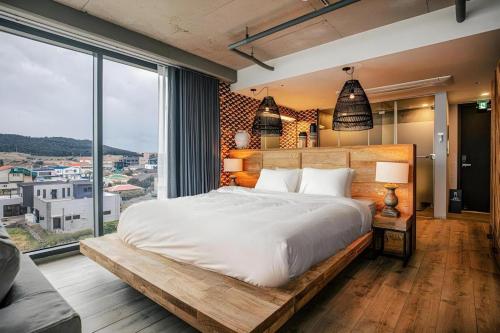 a bedroom with a large bed and a large window at Tropical Hideaway in Seogwipo