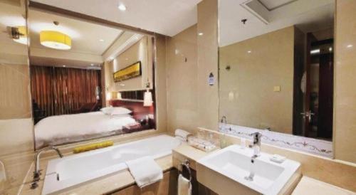a bathroom with a tub and a large mirror at Ramada by Wyndham Zibo in Zibo