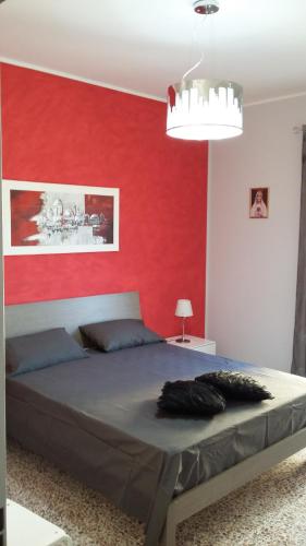 a bedroom with a large bed with a red wall at La Casa sul Corso in Campora San Giovanni