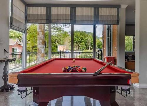 einem Billardtisch vor einem großen Fenster in der Unterkunft Chateau de Luxi Khao Yai - ชาโตว์ เดอ ลูซี่ เขาใหญ่ in Mu Si
