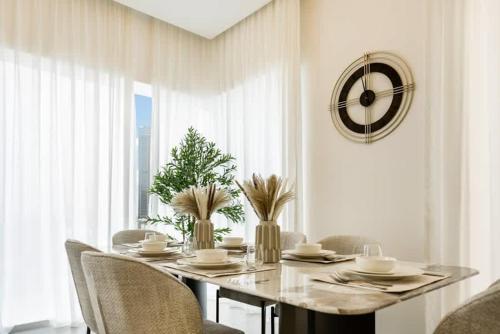 a dining room table with chairs and a clock on the wall at FAM Living - 3 bedroom and Maids Room Retreat Overlooking Dubai Canal in Dubai