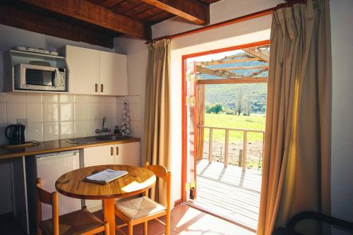 a kitchen with a table and a door to a balcony at Wilgewandel Holiday Farm & Day Restaurant in Oudtshoorn