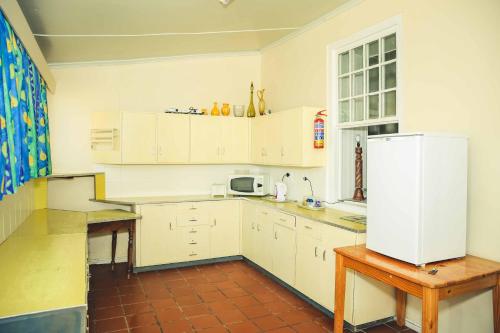 a kitchen with white cabinets and a white refrigerator at Wilgewandel Holiday Farm & Day Restaurant in Oudtshoorn