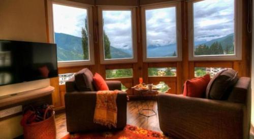 Una sala de estar con dos sofás y un televisor con ventanas. en The Pema by Realm, en Thimphu