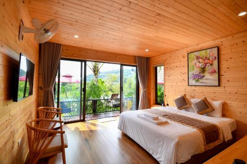 a bedroom with a bed and a large window at San Signature - Suối Ngọc Retreat in Tien Xuan