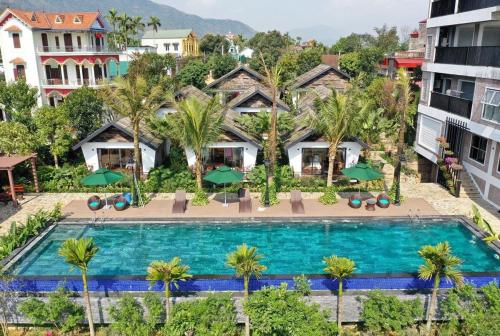 an aerial view of a resort swimming pool with palm trees at San Signature - Suối Ngọc Retreat in Tien Xuan